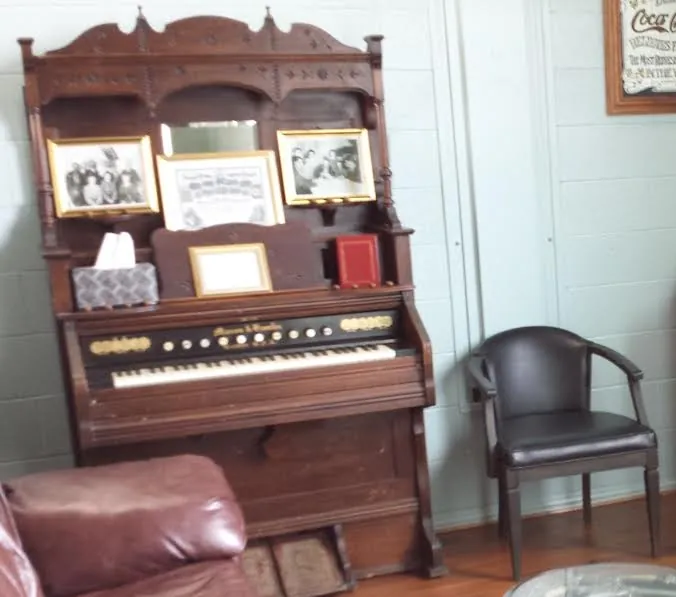 A pump organ with framed black-and-white photos on top